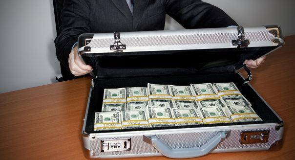 Man holding silver briefcase full of 0 bills