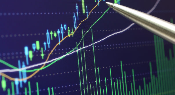 Close-up of a ballpoint pen pointing at the stock quote chart on a computer monitor.