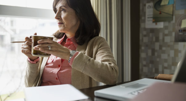 Pensive woman drinking coffee in home office